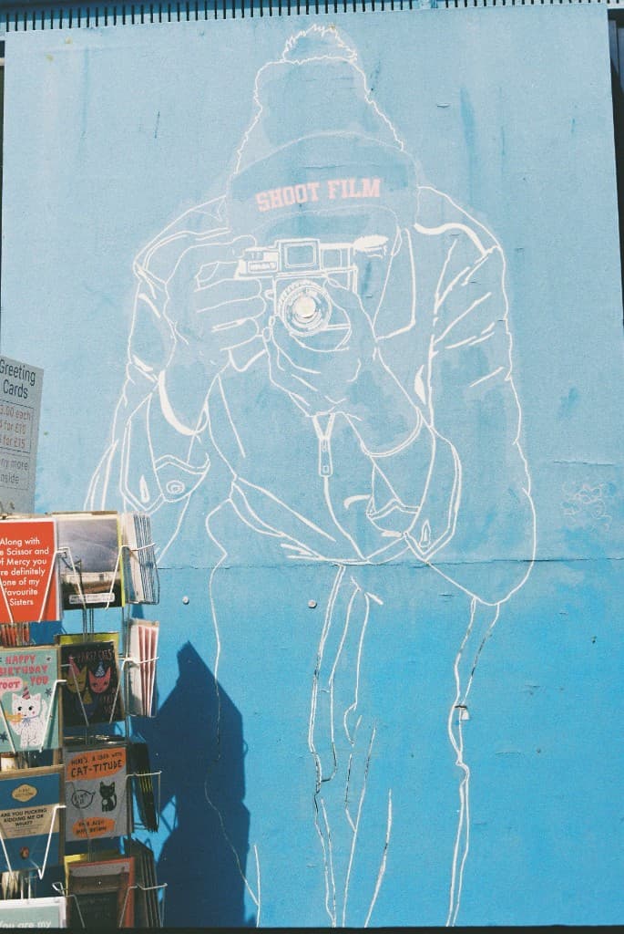 A street mural of a photographer holding a camera up to shoot